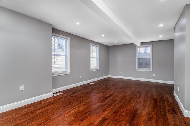 unfurnished room featuring dark hardwood / wood-style flooring and beamed ceiling