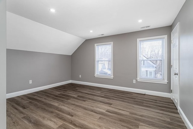 bonus room with plenty of natural light, dark wood-type flooring, and vaulted ceiling