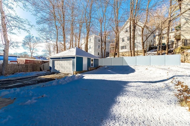 yard covered in snow featuring a garage and an outbuilding