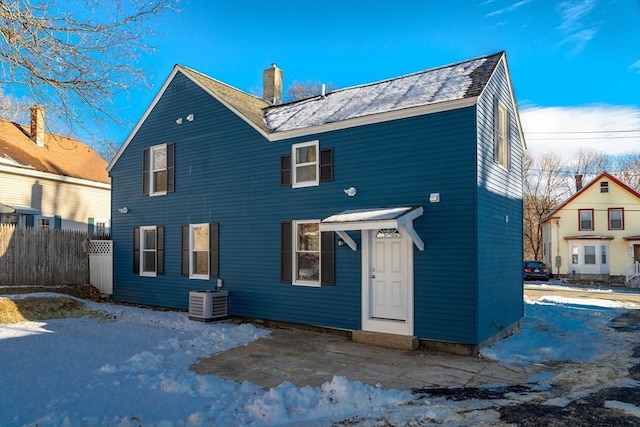 snow covered back of property featuring central AC