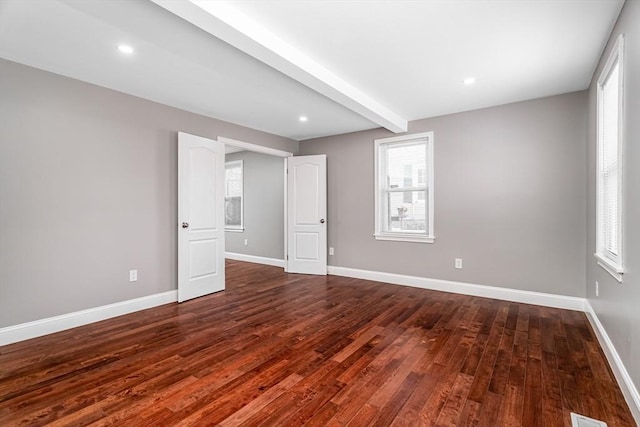 spare room with beam ceiling and dark hardwood / wood-style flooring