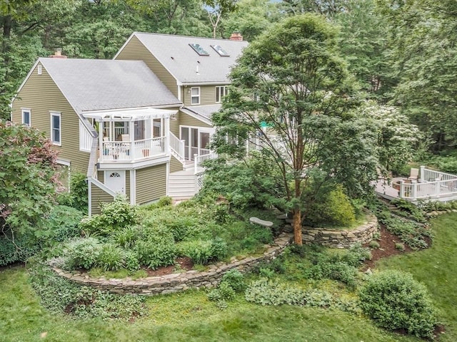 rear view of property featuring a sunroom, a chimney, stairway, and a deck