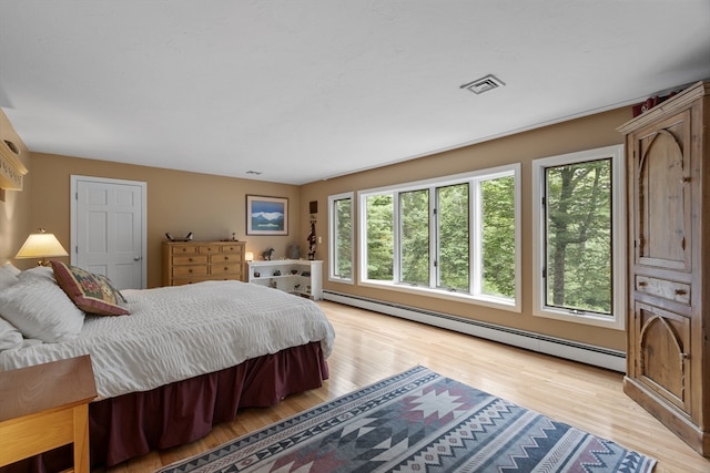 bedroom with light wood-type flooring and a baseboard heating unit