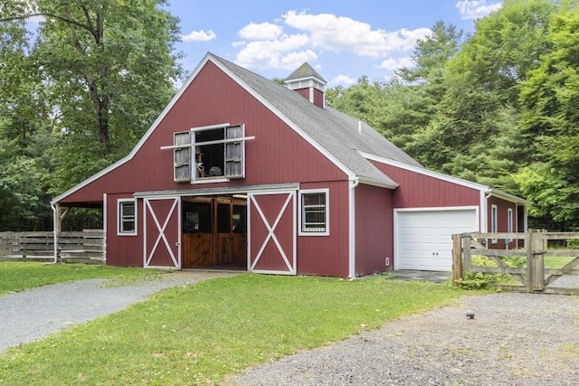 view of barn with driveway and fence