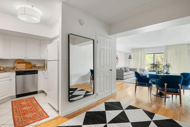 135 Pleasant St Unit 403, Brookline, MA 02446 - kitchen featuring dishwasher, freestanding refrigerator, white cabinetry, light stone counters, and open floor plan
