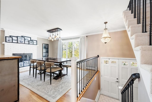 37 Hillcrest Ave, Methuen, MA 01844 - dining room with a chandelier, crown molding, a brick fireplace, baseboards, and light wood-type flooring
