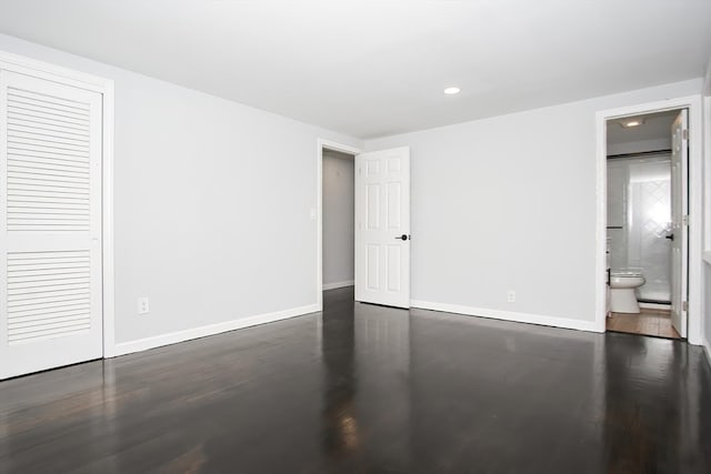 unfurnished bedroom featuring connected bathroom, a closet, and dark hardwood / wood-style floors