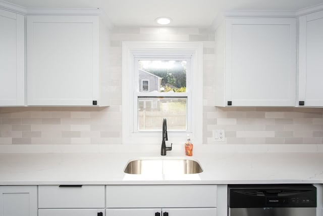 kitchen with stainless steel dishwasher, sink, white cabinetry, and backsplash