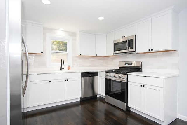 kitchen with sink, dark hardwood / wood-style flooring, white cabinetry, stainless steel appliances, and decorative backsplash