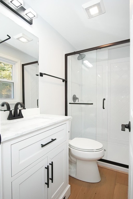 bathroom with vanity, toilet, an enclosed shower, and hardwood / wood-style floors