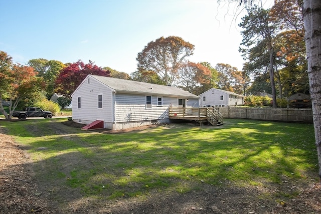 rear view of house featuring a wooden deck and a lawn