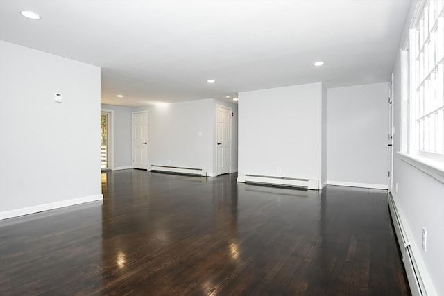 spare room featuring baseboard heating and dark wood-type flooring