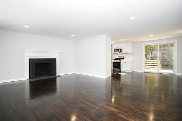 unfurnished living room with dark wood-type flooring and a brick fireplace