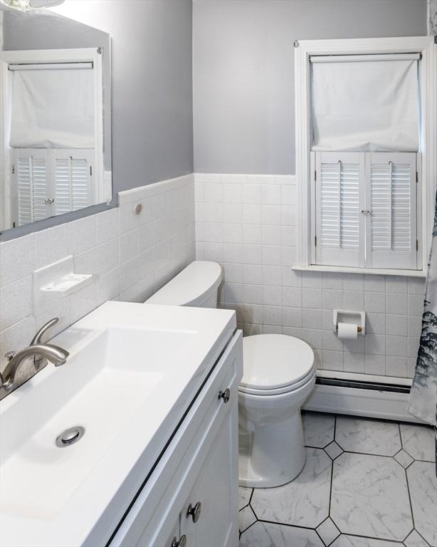 67 Donbray Rd, Springfield, MA 01119 - bathroom with baseboard heating, vanity, toilet, tile walls, and marble look tiles