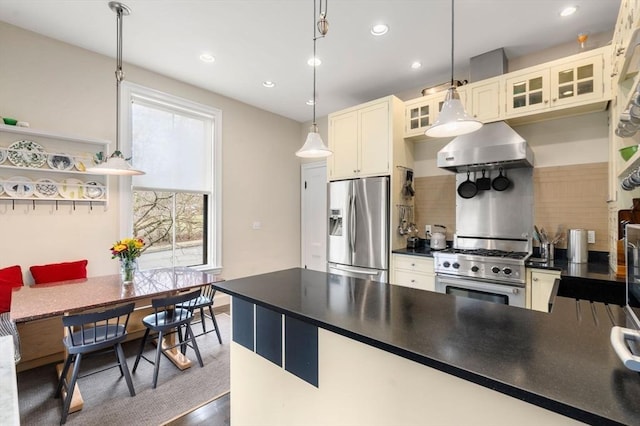 kitchen with pendant lighting, glass insert cabinets, stainless steel appliances, dark countertops, and extractor fan