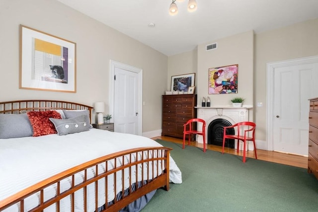 carpeted bedroom with baseboards, a fireplace, and visible vents