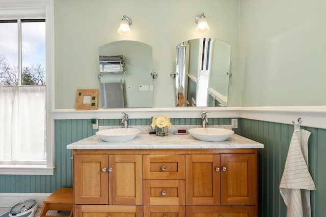 full bathroom featuring a wainscoted wall, a sink, and plenty of natural light