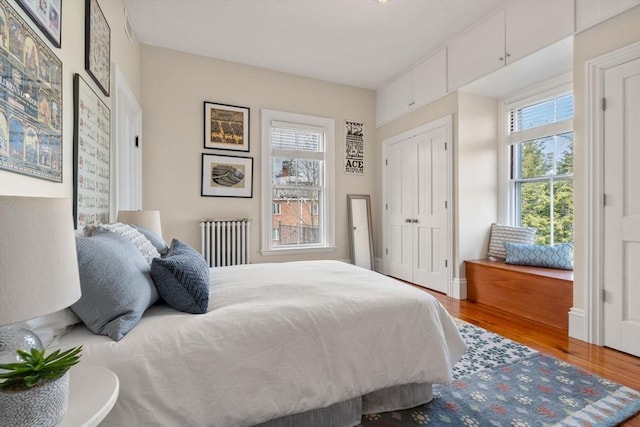 bedroom featuring a closet, visible vents, wood finished floors, and radiator heating unit