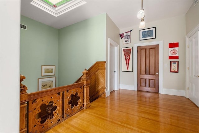 foyer entrance with light wood-type flooring, a skylight, baseboards, and visible vents