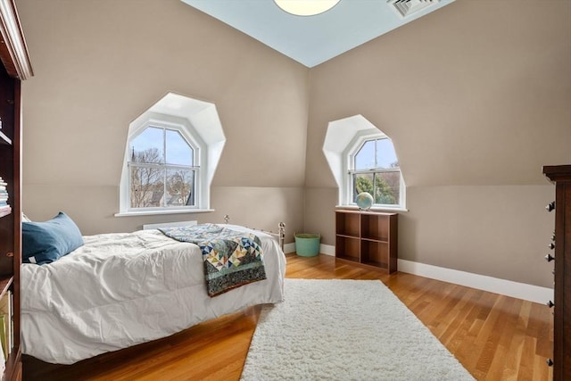 bedroom with visible vents, baseboards, and wood finished floors