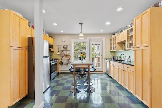 kitchen featuring a sink, glass insert cabinets, light brown cabinets, stainless steel appliances, and dark floors