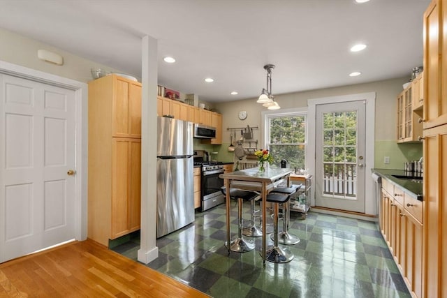 kitchen featuring tasteful backsplash, recessed lighting, dark countertops, light brown cabinets, and appliances with stainless steel finishes