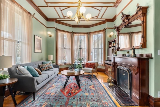 living area with light wood finished floors, a notable chandelier, crown molding, and a fireplace with flush hearth