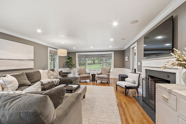 22 High St, Southborough, MA 01772 - living room with light wood-style flooring, a wainscoted wall, ornamental molding, a fireplace with flush hearth, and recessed lighting