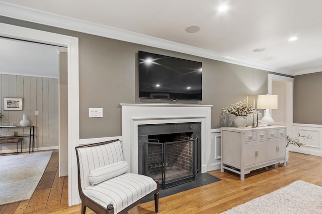 22 High St, Southborough, MA 01772 - living area featuring light wood-type flooring, crown molding, a fireplace with flush hearth, a decorative wall, and a wainscoted wall