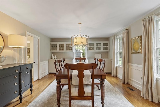 22 High St, Southborough, MA 01772 - dining room with light wood-style floors, a decorative wall, a chandelier, and wainscoting