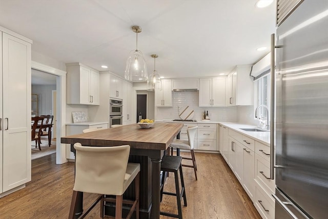 22 High St, Southborough, MA 01772 - kitchen featuring stainless steel appliances, butcher block counters, a kitchen breakfast bar, wood finished floors, and recessed lighting