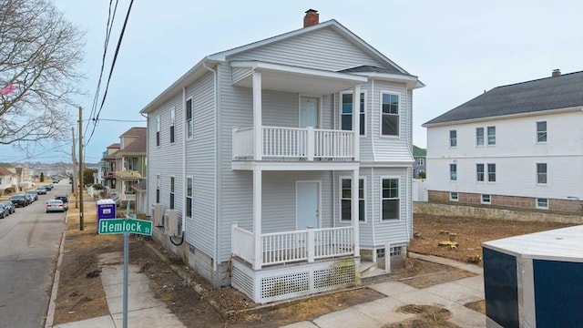 view of front of home featuring a balcony, covered porch, and a chimney