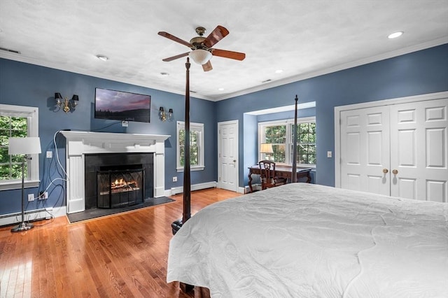 38 Lincoln Cir E, Andover, MA 01810 - bedroom with multiple closets, baseboard heating, wood finished floors, a warm lit fireplace, and recessed lighting