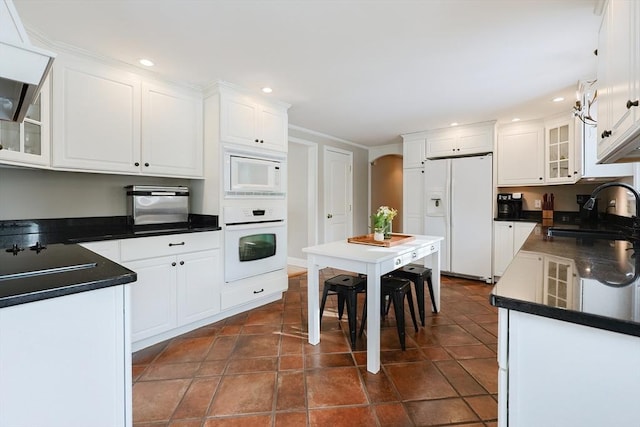 kitchen with white cabinetry, sink, dark tile patterned floors, custom range hood, and white appliances