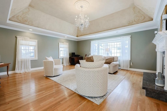 living room with crown molding, a tray ceiling, and light hardwood / wood-style flooring