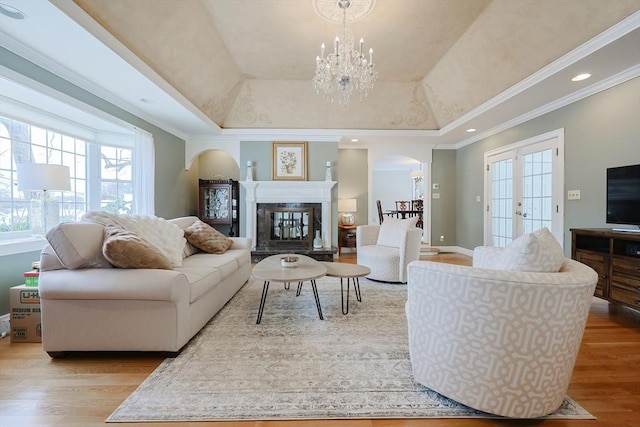 living room with an inviting chandelier, light hardwood / wood-style floors, and a tray ceiling