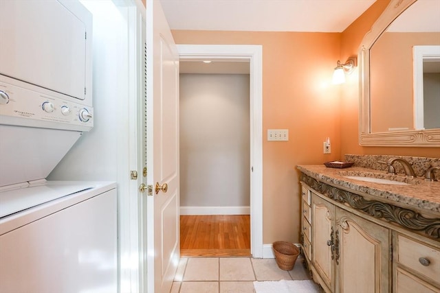 bathroom with tile patterned flooring, stacked washer and dryer, and vanity