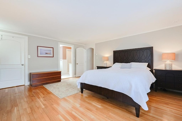 bedroom with connected bathroom and light wood-type flooring