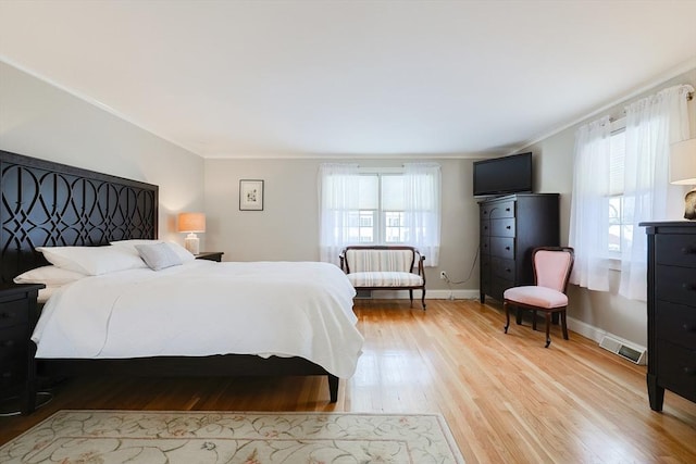 bedroom featuring multiple windows, crown molding, and light hardwood / wood-style floors