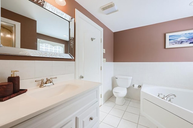 bathroom with tile patterned flooring, tile walls, a bathing tub, vanity, and toilet