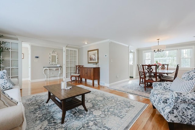 living room with crown molding, light hardwood / wood-style flooring, and a chandelier