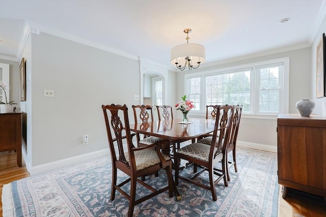 dining space featuring ornamental molding, an inviting chandelier, and light hardwood / wood-style floors