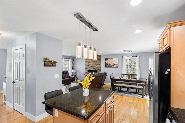 29 Regatta Dr, Attleboro, MA 02703 - kitchen with a fireplace, open floor plan, freestanding refrigerator, light wood-style floors, and dark stone counters