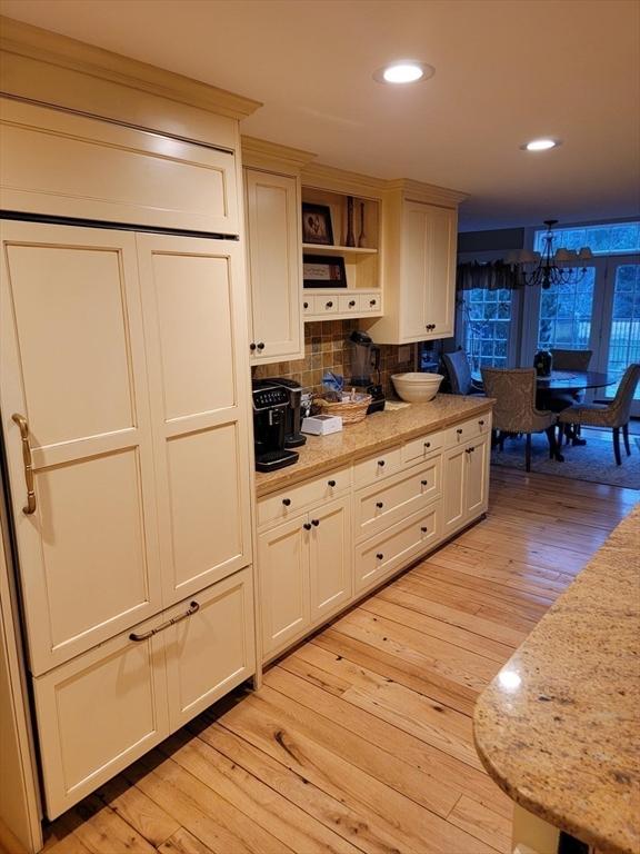 kitchen with tasteful backsplash, light hardwood / wood-style flooring, and light stone counters