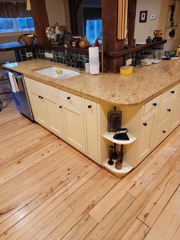 kitchen featuring sink, dishwasher, light stone counters, and light hardwood / wood-style floors