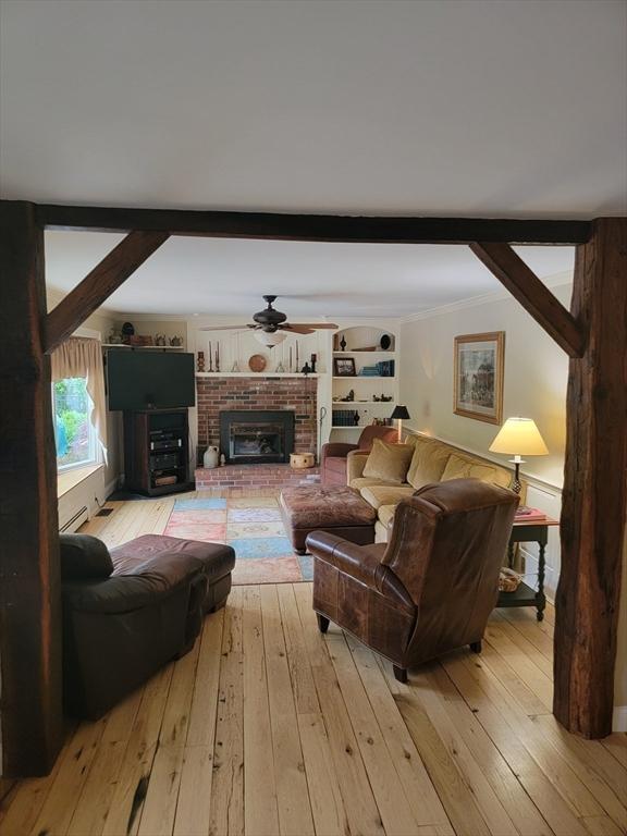 living room with ceiling fan, beam ceiling, light hardwood / wood-style floors, and a fireplace