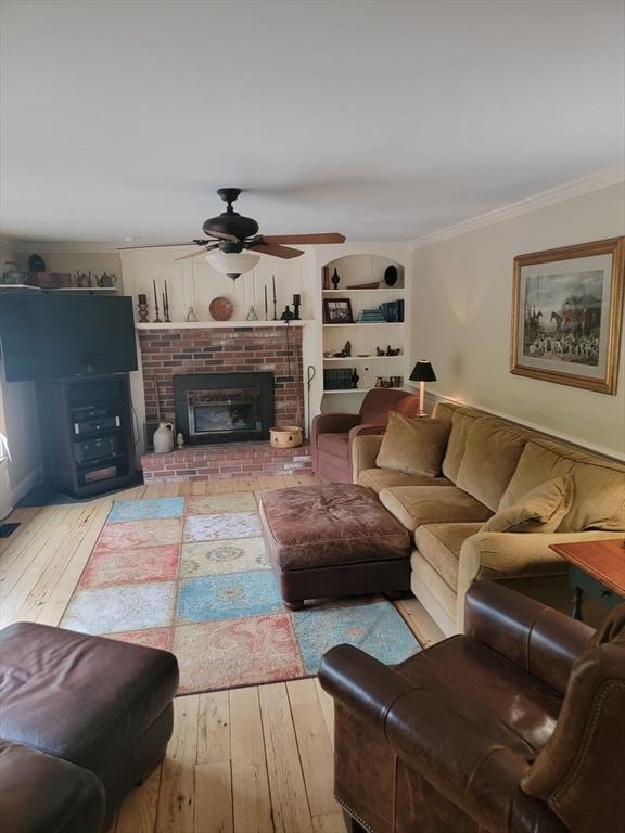 living room with ceiling fan, light hardwood / wood-style floors, a brick fireplace, and ornamental molding