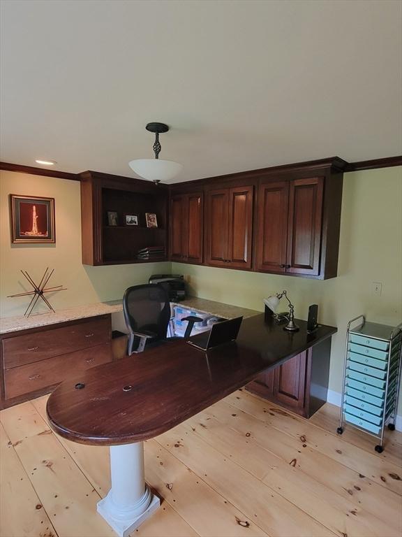 office space with ornamental molding, built in desk, and light hardwood / wood-style flooring