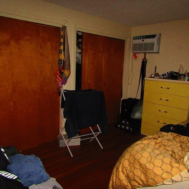 bedroom with an AC wall unit, a closet, and dark hardwood / wood-style flooring