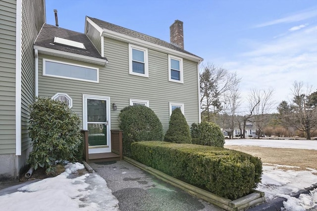 exterior space with a shingled roof and a chimney